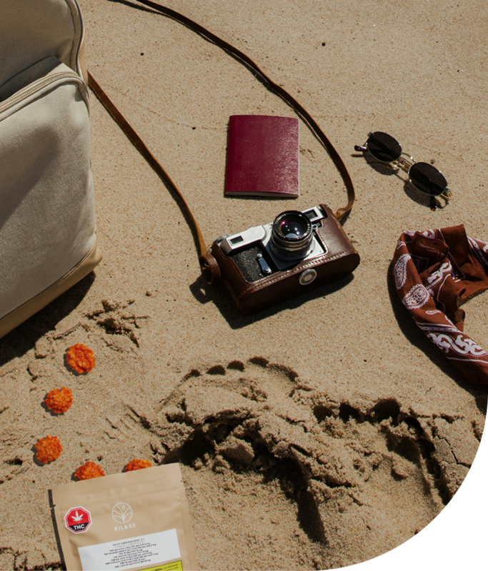 Rilaxe cannabis edibles with summer essentials on a sandy beach